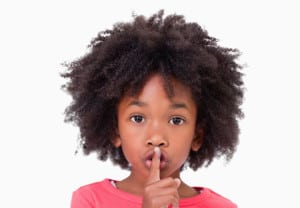 Close up of a girl asking silence against a white background